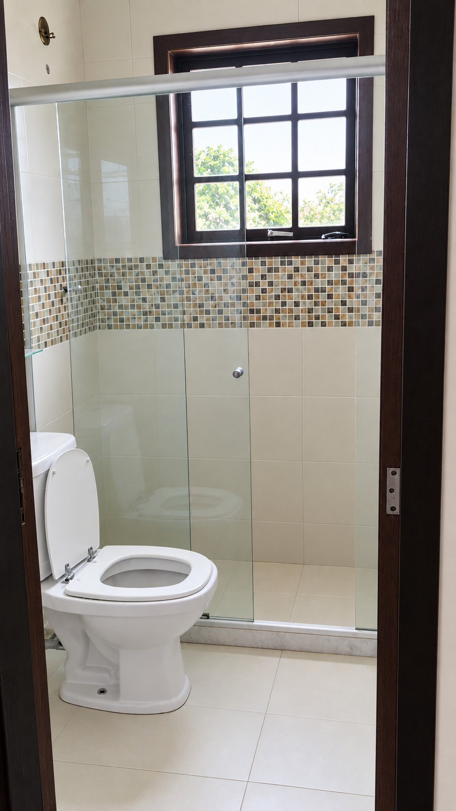 Banheiro com box de vidro e revestimento em mosaico